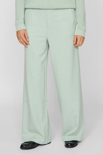 Pantalon vert de VILA, avec des jambes larges et porté avec des chaussures noires.
