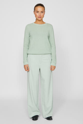 Pantalon vert de VILA, associé à un pull vert et des chaussures noires, présenté debout contre un fond neutre.