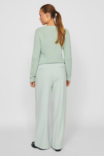 Pantalon vert de VILA, avec des jambes larges et porté avec un pull tricoté vert.