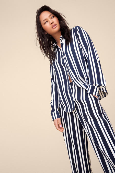 Blauwe broek van VILA® met witte strepen, gecombineerd met een gestreepte blouse.
