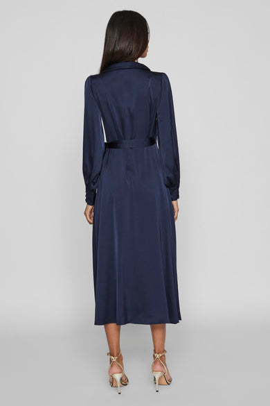 Blauwe lange mouwen kleedje van VILA, met riem in de taille en gouden hakken.
