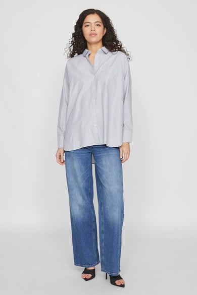 Blauw hemd met lange mouwen van VILA®, gedragen met wijde jeans en hakken.