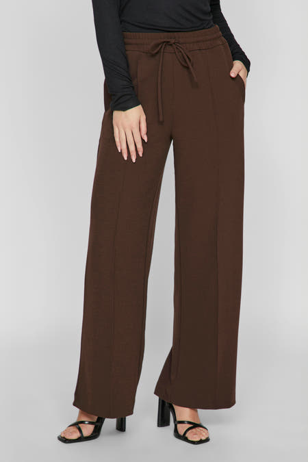 Pantalon marron de VILA®, avec des jambes larges, une ceinture à la taille et des sandales noires.
