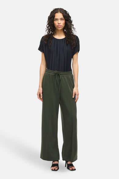 Pantalon vert de VILA®, avec cordon et jambes larges, porté avec une chemise plissée et des talons hauts.