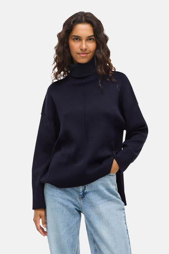 T-shirt bleu avec col montant de VILA, porté avec des jeans bleus clairs et une main dans la poche.