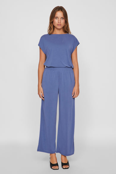 Blauwe broek van VILA, met wijde pijpen en een elastische tailleband, gedragen met zwarte muiltjes.

