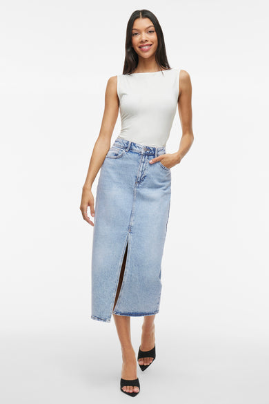 Lichtblauwe denim rok van VILA, met een split aan de voorkant, gecombineerd met een witte top en zwarte hakken.
