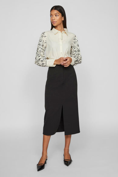 Zwarte lange rok van VILA, met een split aan de voorkant, gecombineerd met een blouse met borduurwerk.
