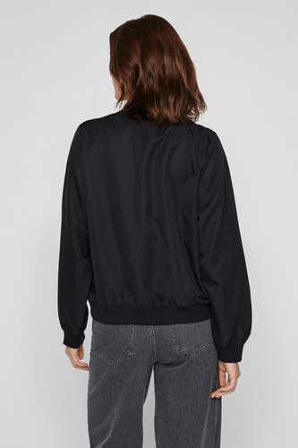 Manteau court noir de VILA, vu de derrière, avec des manches longues et un jeans gris.