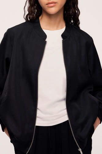 Manteau noir de VILA, porté ouvert sur un chemisier blanc et un pantalon noir.