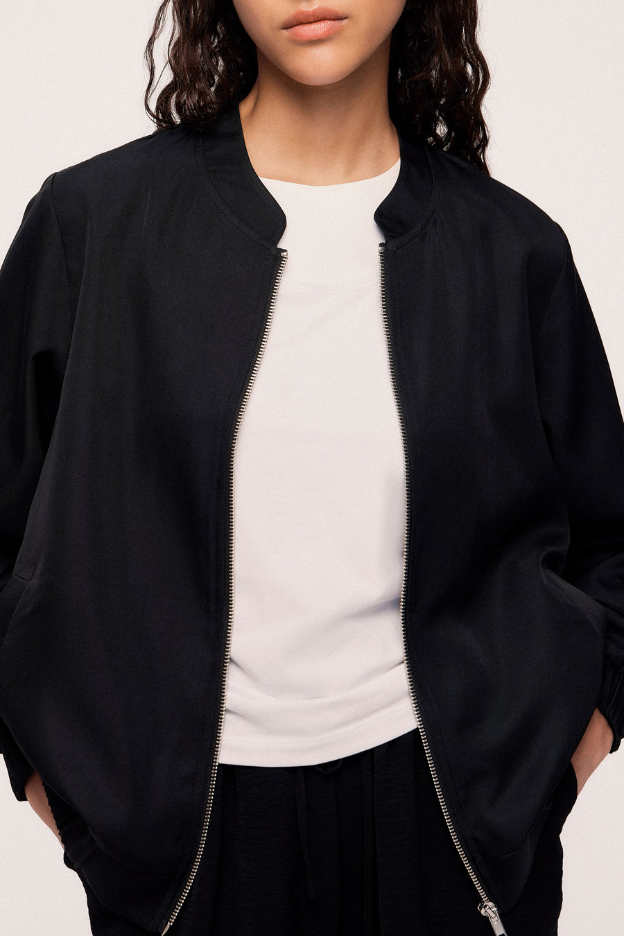 Manteau noir de VILA, porté ouvert sur un chemisier blanc et un pantalon noir.