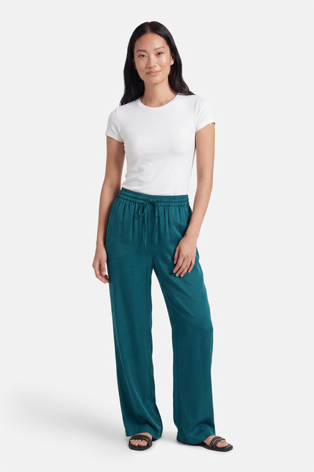 Groene broek van VILA® met wijde pijpen, elastische taille en trekkoord, gedragen met een wit T-shirt en sandalen.