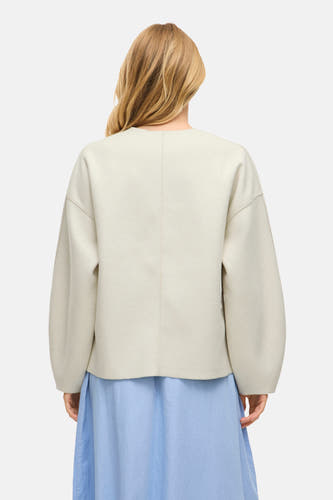 Crème court manteau de VILA®, vu de derrière, combiné avec une jupe bleu clair.