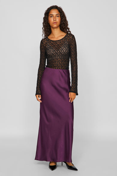 Zwarte blouse met lange mouwen van VILA, gedragen met een paarse, satijnen rok en zwarte hakken.
