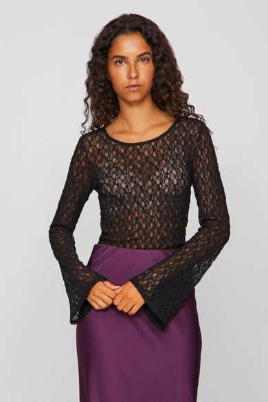 Zwarte blouse met lange mouwen van VILA®, met een open kantpatroon en wijde mouwen, gecombineerd met een paarse rok.
