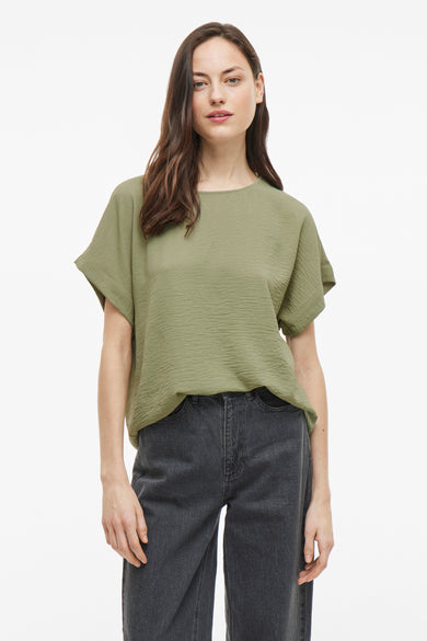 T-shirt vert avec manches courtes de VILA®, porté avec des jeans gris foncé et des escarpins noirs.