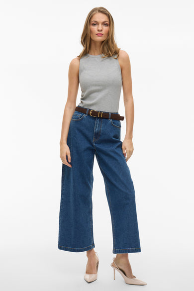 Grijs mouwloos top van VILA, gedragen met blauwe jeans met bruine riem en beige hakken.
