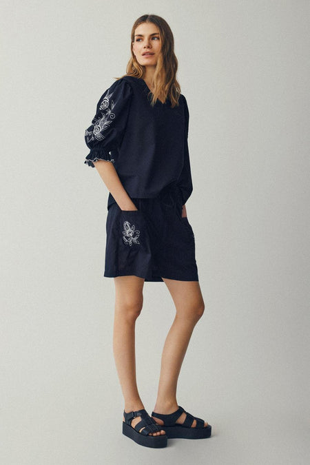 Zwarte blouse met driekwart mouwen van VILA®, voorzien van witte geborduurde details op de mouwen en shorts.