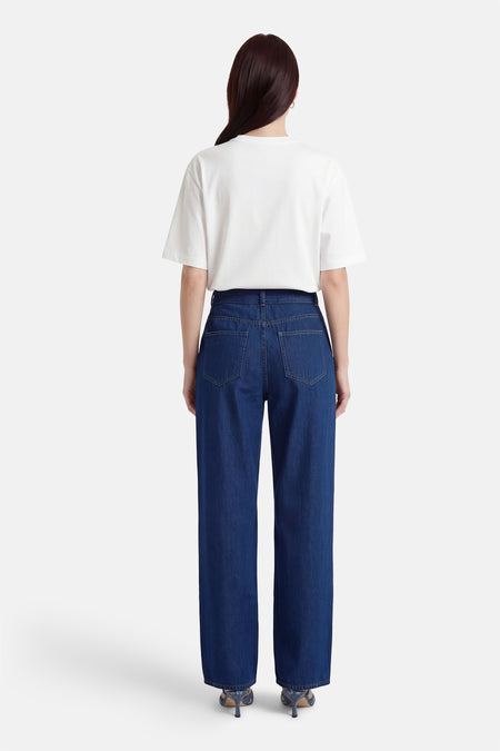 Jean droit bleu foncé de VILA®, vu de dos, associé à un t-shirt blanc et des talons bleus.