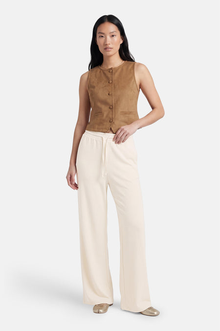 Pantalon beige de VILA®, à jambe large et cordon de serrage, porté avec un gilet marron et des chaussures dorées.