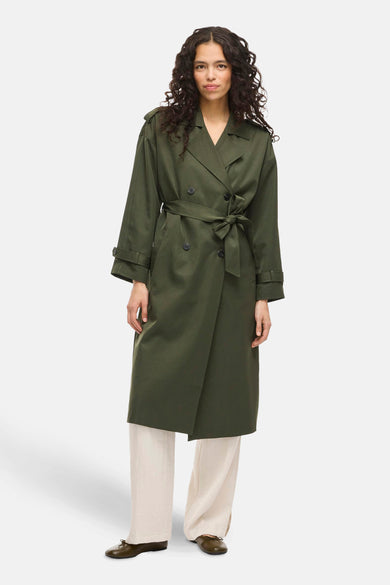 Groene jas van VILA®, met een knoopceintuur en gedragen over een crèmekleurige broek.
