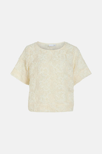 Blouse beige à manches courtes de VILA®, avec un motif floral subtil et une douce texture.