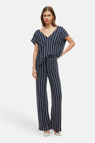 Pantalon bleu de VILA, avec un motif à carreaux zigzag et des jambes larges, stylé avec des escarpins pointus.