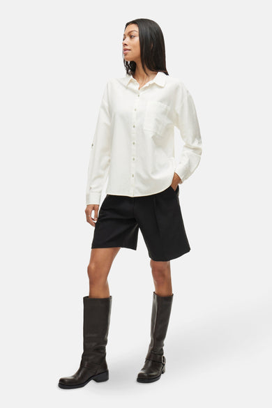 Wit overhemd met lange mouwen van VILA®, gedragen met zwarte shorts en hoge laarzen.
