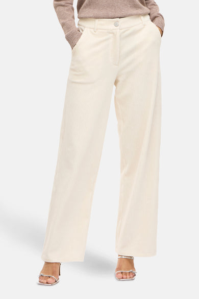 Pantalon beige de VILA, avec une texture corduroy et des jambes larges, associé à des sandales argentées.