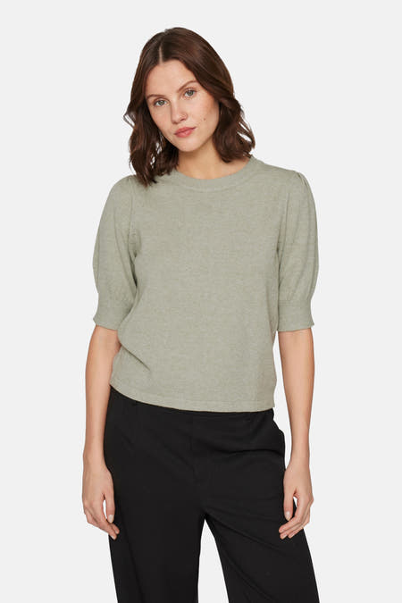Groene trui met korte pofmouwen van VILA, gedragen met een zwarte pantalon.
