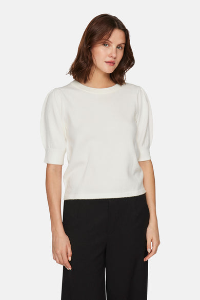 Pull blanc à col rond de VILA, avec manches courtes bouffantes, porté avec un pantalon noir ample.