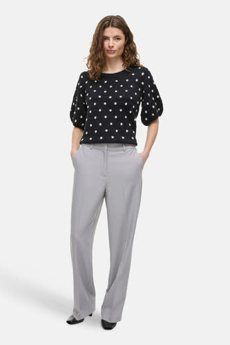 Grijze broek van VILA®, gecombineerd met een zwarte trui met witte stippen en zwarte hakken.

