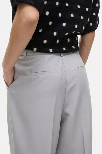 Grijze broek van VILA, met achterzakken, gecombineerd met een zwart truitje met stippen.