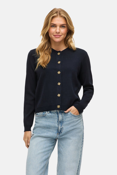 Blauw vest van VILA, met lange mouwen en knoopsluiting, gedragen met een spijkerbroek.
