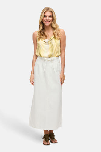 Witte lange rok van VILA®, met strikceintuur en gedragen met een gele top en bruine sandalen.
