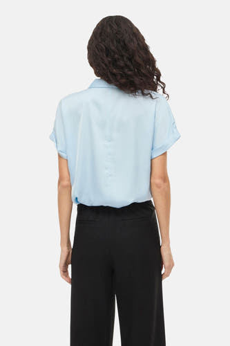 Blauwe blouse met korte mouwen van VILA, gezien van achteren, gecombineerd met een zwarte broek.
