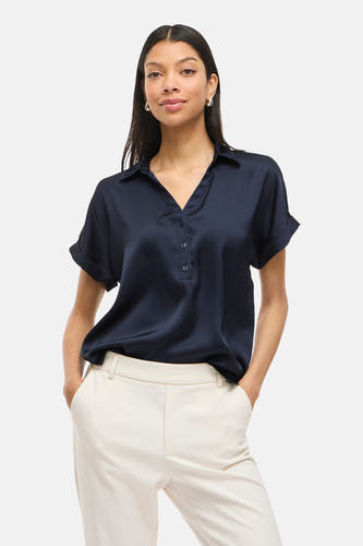 Blauwe blouse met korte mouwen van VILA®, met knoopsluiting en gedragen met een crèmekleurige pantalon.
