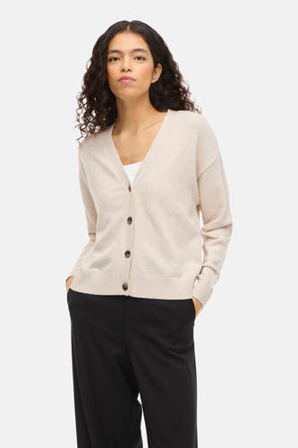 Gilet écru de VILA®, à manches longues et fermeture boutonnée, porté avec un haut blanc et un pantalon noir.