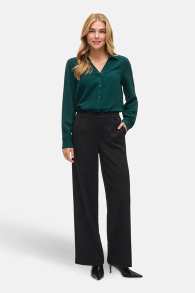 Groene blouse met lange mouwen van VILA®, met knoopsluiting en gedragen met zwarte pantalon en hakken.
