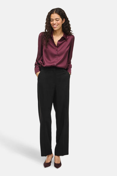 Bordeaux hemd met lange mouwen van VILA®, met knoopsluiting en gedragen met een zwarte pantalon en bordeaux hakken.
