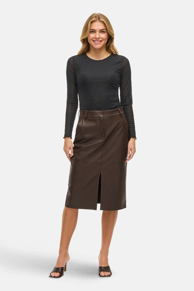 Zwart T-shirt met lange mouwen van VILA®, gedragen met een bruine leren rok met split en hakken.
