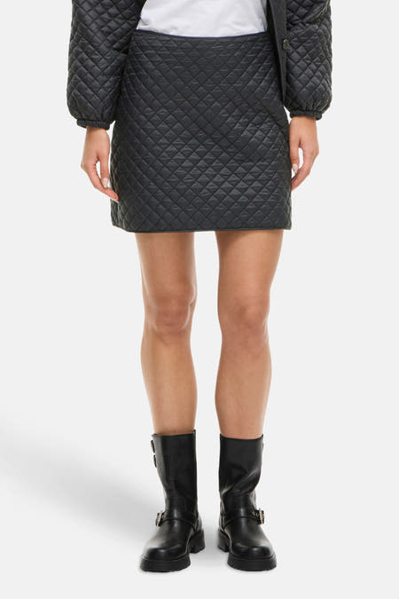 Jupe courte noire de VILA, avec un motif à carreaux rayé, associée à des bottes noires.