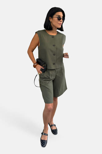 Groen gilet van VILA, gedragen met bijpassende shorts en zwarte sandalen met studs.
