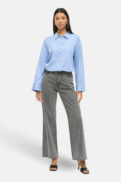 Donkergrijze wide jeans van VILA, met verticale strepen en gecombineerd met een lichtblauw overhemd.