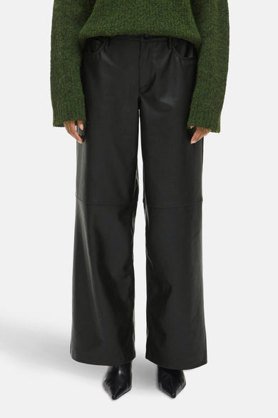 Pantalon noir de VILA, avec des jambes larges et associé à une chemise verte et des baskets noires.