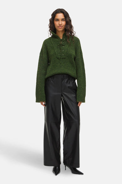 Zwarte broek van VILA, met wijde pijpen en gecombineerd met een groene trui en zwarte hakken.