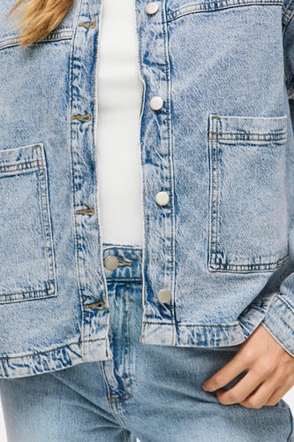 Lichtblauwe denim jeansjas van VILA® met zilveren knopen en zakken, gedragen over een wit topje en bijpassende jeans.
