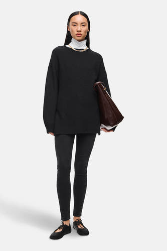 Zwarte skinny jeans van VILA®, gecombineerd met zwarte trui, witte blouse, gouden ketting en een leren tas.