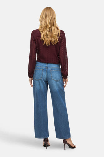 Blauwe wijde jeans van VILA, met zichtbare achterzakken en gedragen met een bordeauxrode blouse.