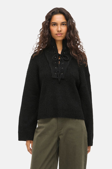 Pull noir de VILA® avec une fermeture à glissière, associé à des pantalons olive et des baskets noires.